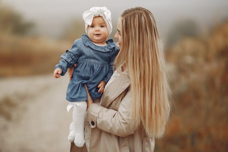 Happy mother standing in park and hugging cute baby